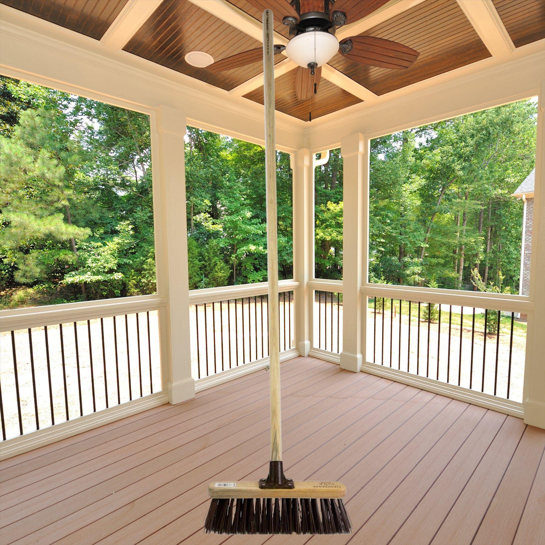 12" Newman & Cole Stiff PVC Broom with Wooden Handle on a houses outdoor wooden patio