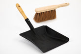 Black dustpan with wooden handle and brush on a white background