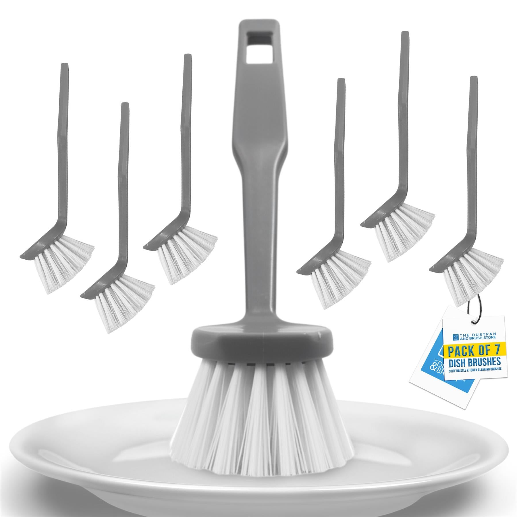 A 7-piece gray plastic dish brush set with white bristles, shown with one larger brush on a white plate and six smaller brushes floating behind it. A hanging tag reads 'PACK OF 7 DISH BRUSHES'.