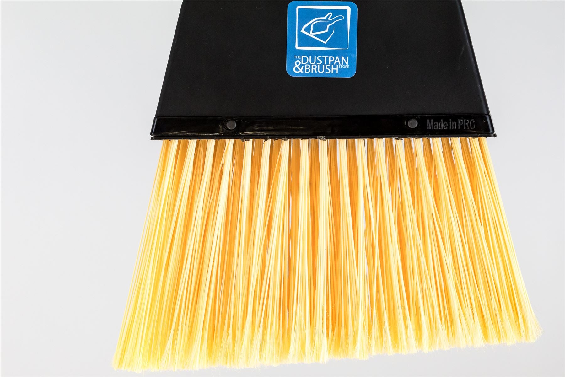 A close-up of a broom head with a black plastic frame and bright yellow nylon bristles, featuring a blue 'ULTRA PAN & BRUSH' logo on the upper frame.
