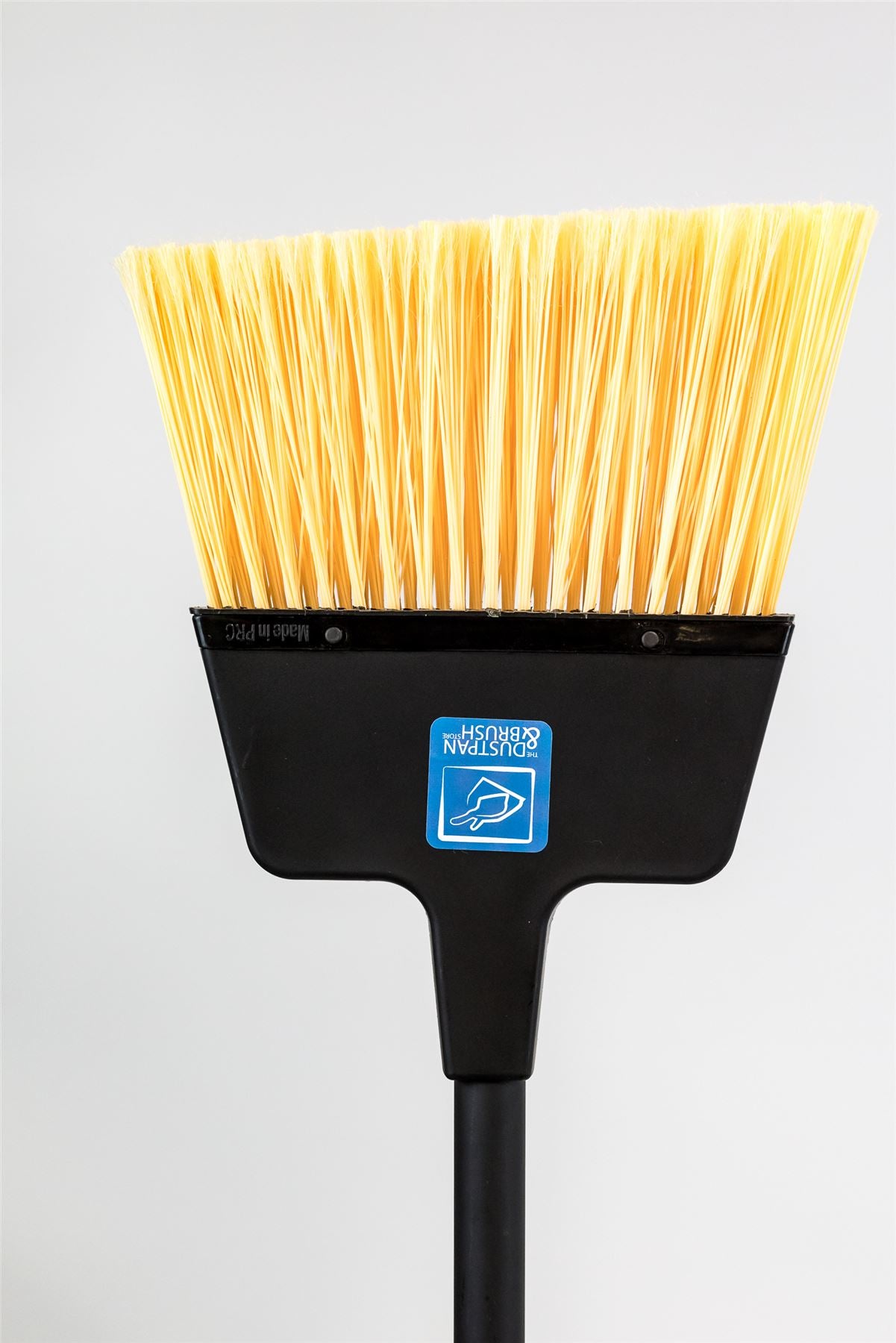 A black plastic push broom with bright yellow bristles, shown against a light gray background. A blue and white 'Made in China' label is visible on the front of the broom head.