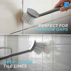 A gray handheld tile brush with white bristles shown cleaning white tiled surfaces, with text reading 'PERFECT FOR NARROW GAPS' and 'DEEP-CLEAN TILE LINES'. A hand is visible holding the brush.