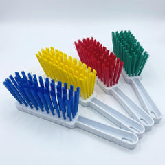 Four plastic cleaning brushes with white handles and colorful bristles in blue, yellow, red, and green, arranged diagonally on a white background.