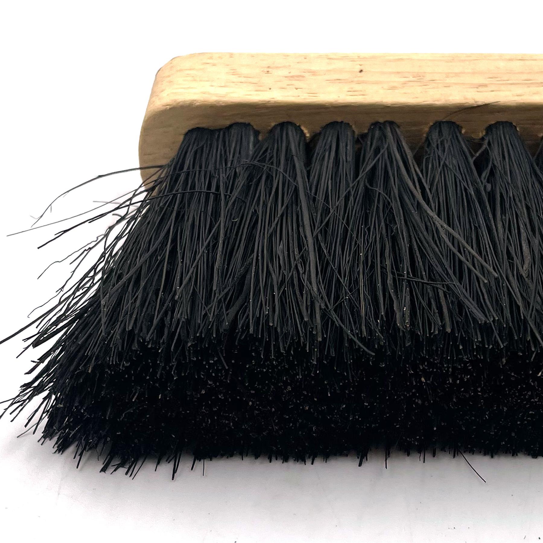 A close-up of a brush with black bristles and a light natural wood handle, shown against a plain white background.