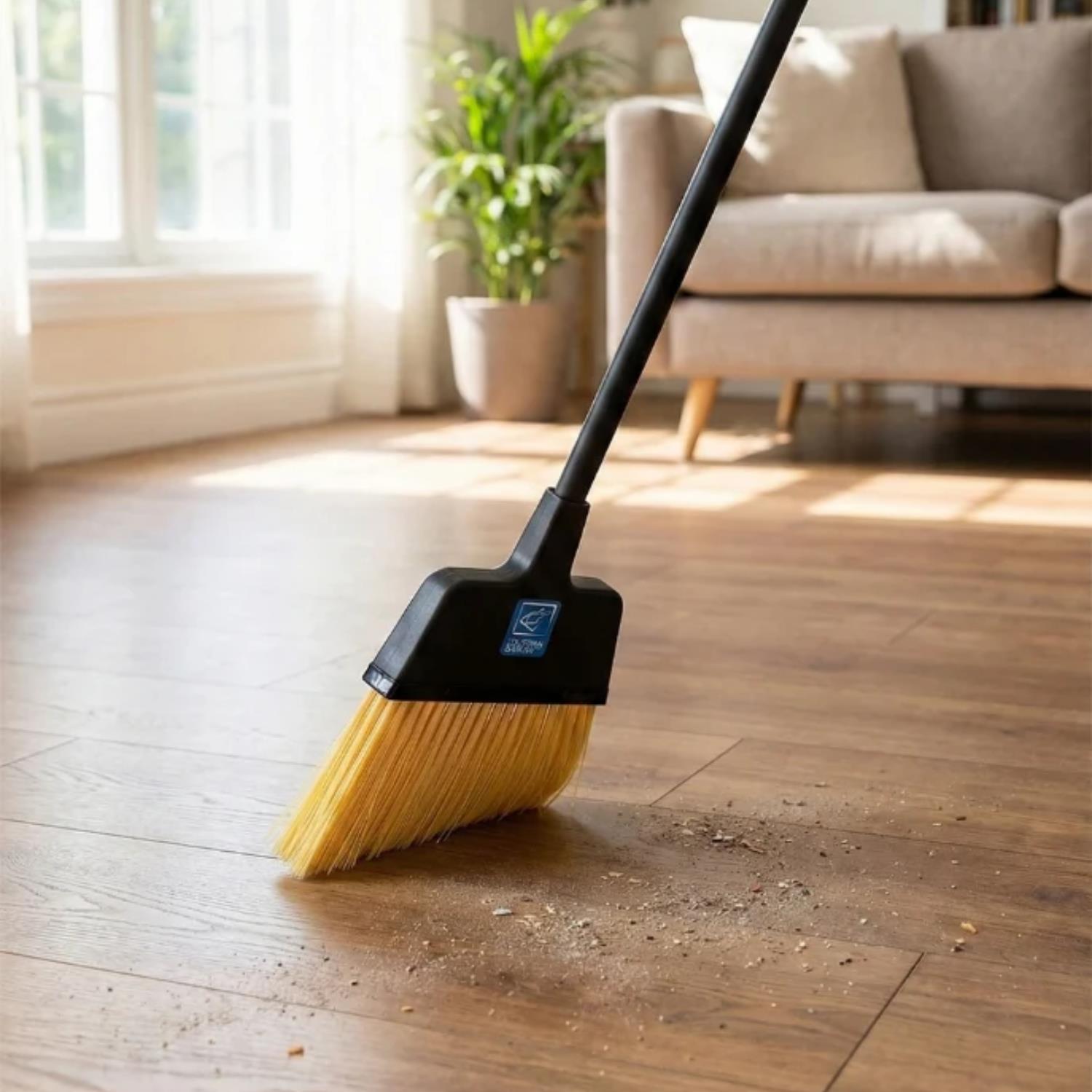 Replacement Stiff Brush for Long Handled Dustpan and Brush Set shown sweeping wood flooring in a bright living room with a sofa and plant in the background.