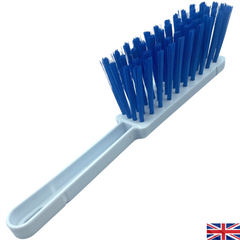 A plastic cleaning brush with a long white handle and dense blue bristles, shown diagonally on a plain white background with a small UK flag icon in the bottom right corner.