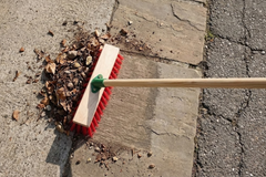 Environmental image of 11.5" Stiff Red PVC Broom Head cleaning outdoor patio and sweeping up leaves 