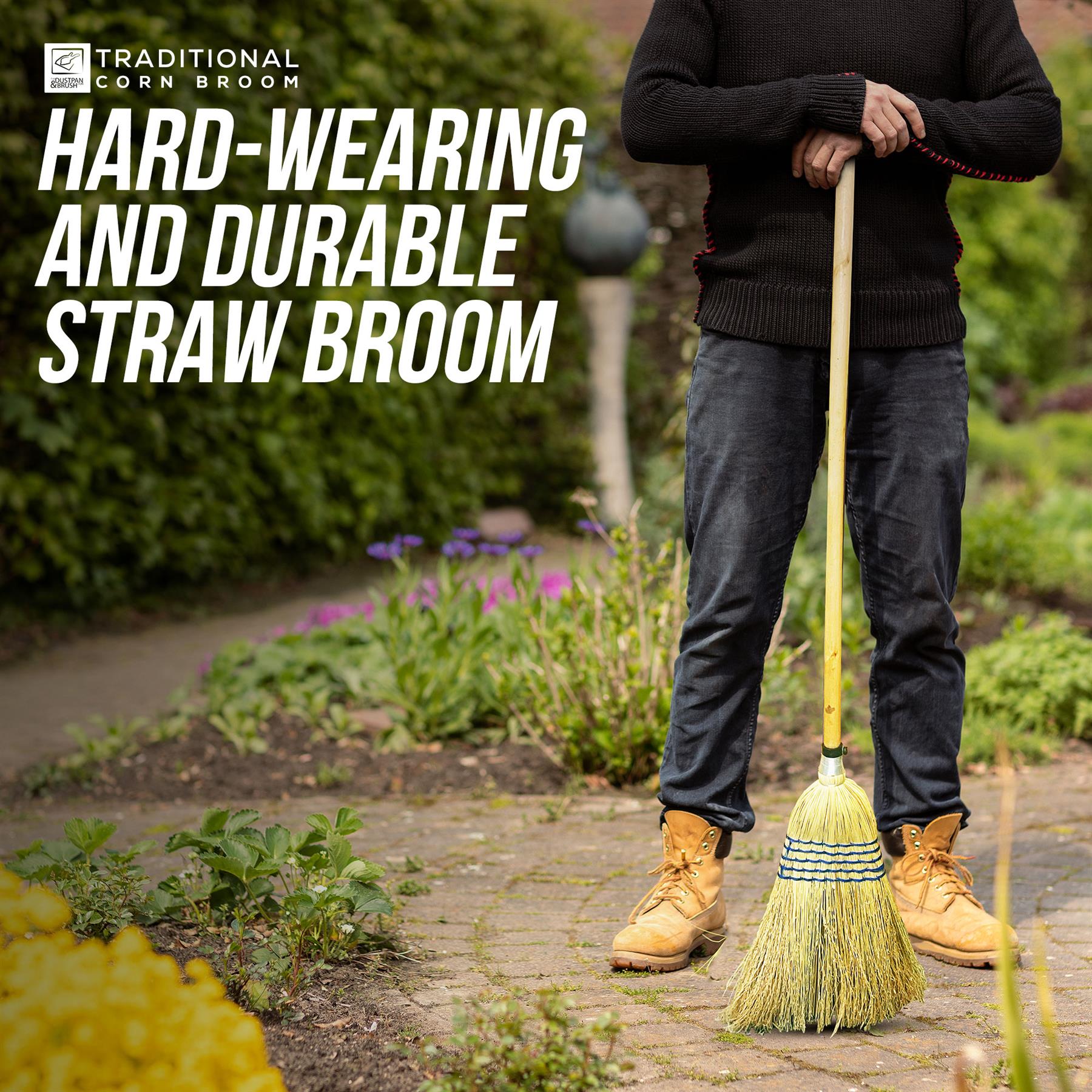A person standing outdoors on a garden path holding a straw broom. Large white text at the top reads 'TRADITIONAL CORN BROOM' and 'HARD-WEARING AND DURABLE STRAW BROOM.