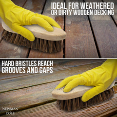 Hand using a brush with hard bristles on wooden decking, wearing yellow gloves.