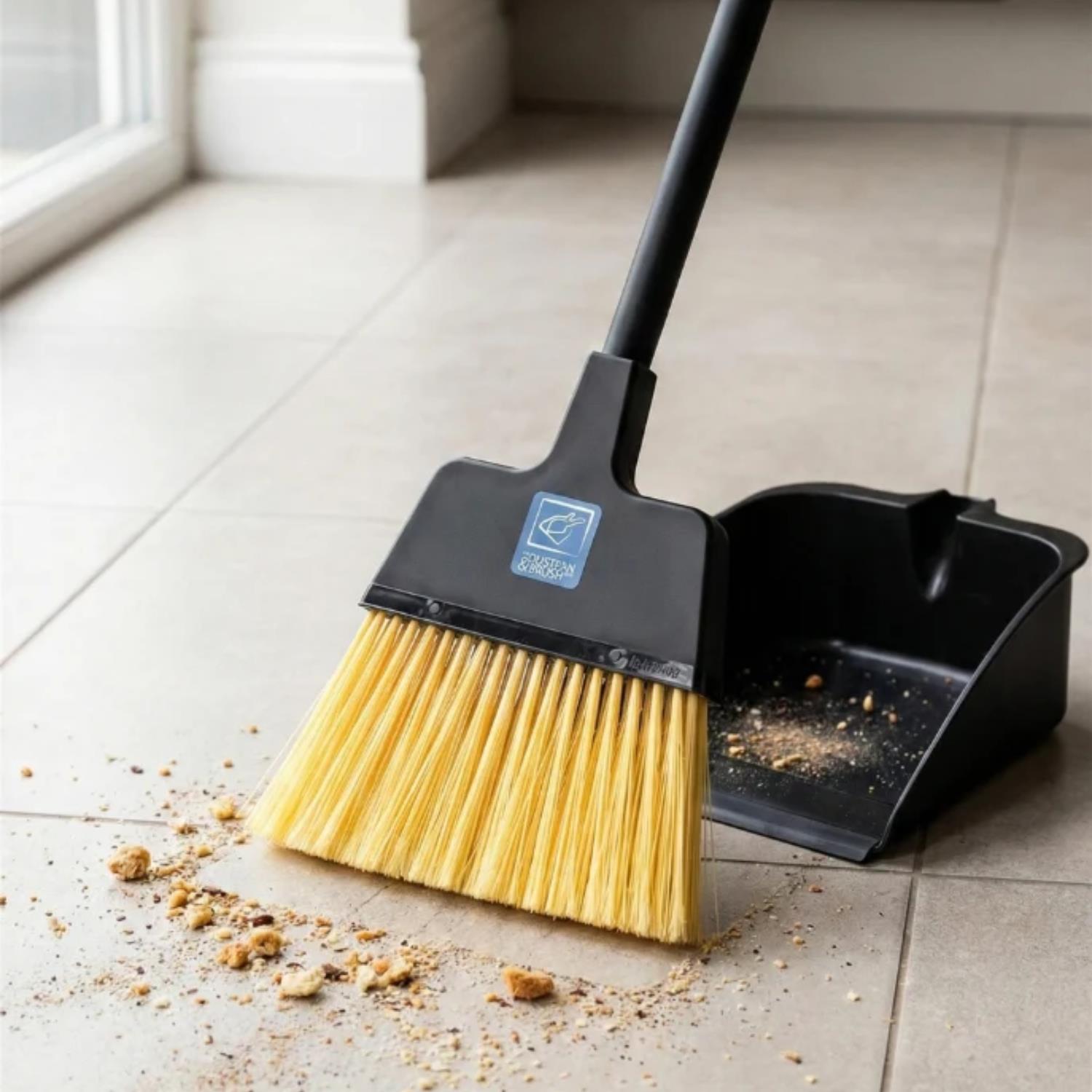 The Replacement Stiff Brush for Long Handled Dustpan and Brush Set with natural yellow bristles, shown on a light beige tiled floor with crumbs being swept up. 