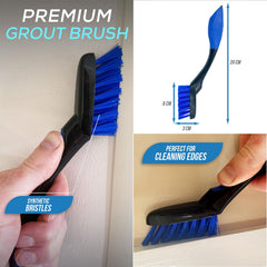 Grout brush with blue bristles being used to clean grout lines on a wall.