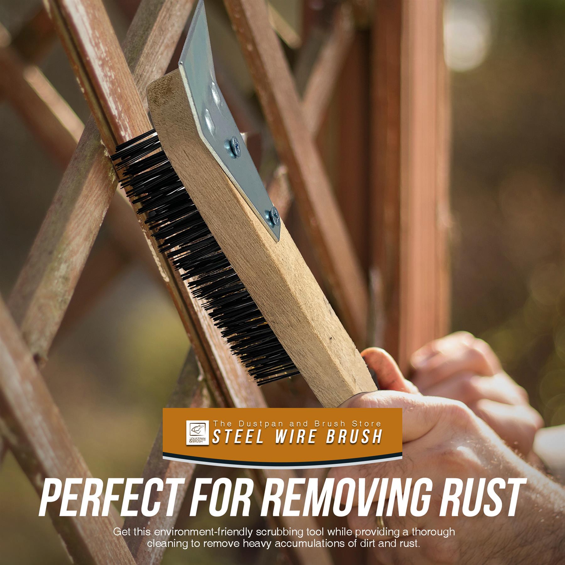 A close-up of a hand holding a wooden-handled steel wire brush against a rusty metal lattice structure, 