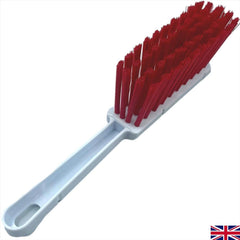 A plastic cleaning brush with a white handle and bright red bristles, shown on a plain white background with a small UK flag icon in the bottom right corner.